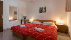 A bedroom with a large bed, two bedside tables, a mirror, and a painting on the wall. - Apartment Anita (Gruž) - One-Bedroom Apartment with Balcony (Dubrovnik)