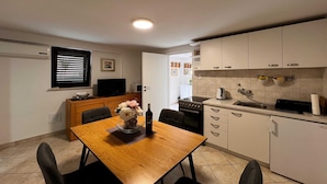 A compact kitchen with a dining table, chairs, a TV, and a refrigerator.