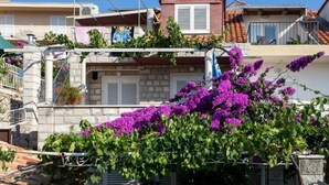 Un immeuble résidentiel aux murs en pierre, doté d’un toit recouvert de tuiles rouges et d’un balcon.