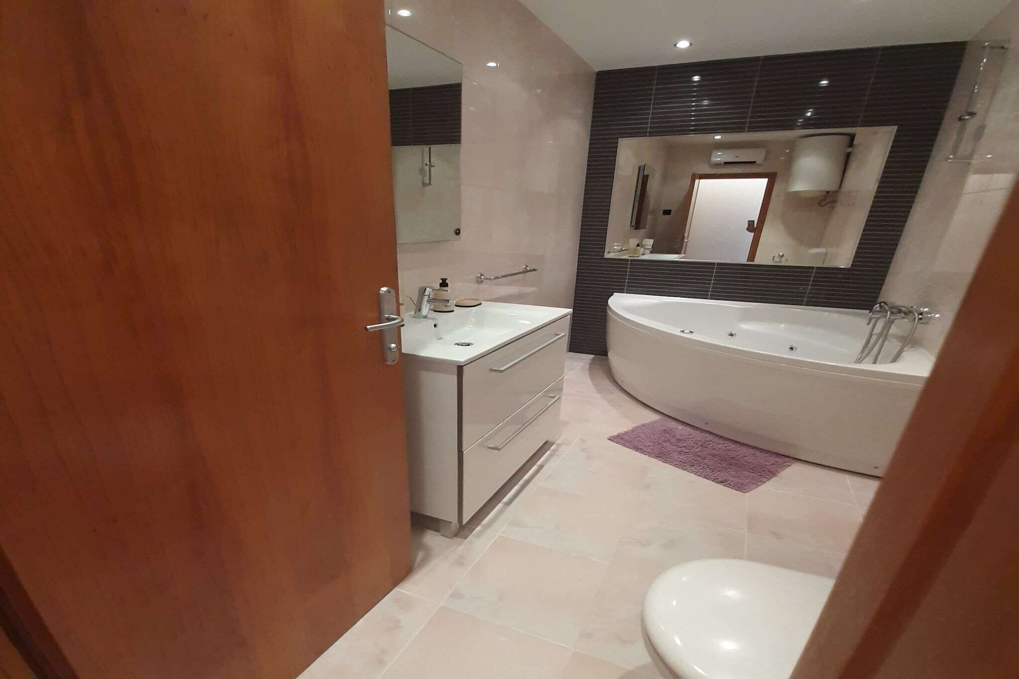 Une salle de bain moderne avec un meuble-lavabo, un évier, un miroir et une baignoire.