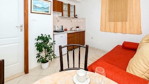 Un espacio habitable compacto con comedor, kitchenette y un sofá con cojines.