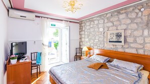 Un dormitorio con cama, televisión, escritorio y pared de piedra.