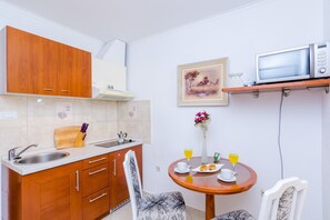 Compact kitchen area with a microwave, table for dining, and a comfortable seating area.
