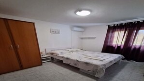 Ein Schlafzimmer mit Bett, Kleiderschrank, Klimaanlage und einem Fenster mit Vorhängen.