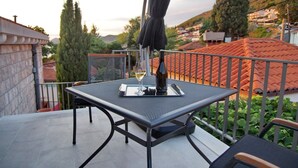 Un balcon avec une table et des chaises, un verre à vin et une bouteille.
