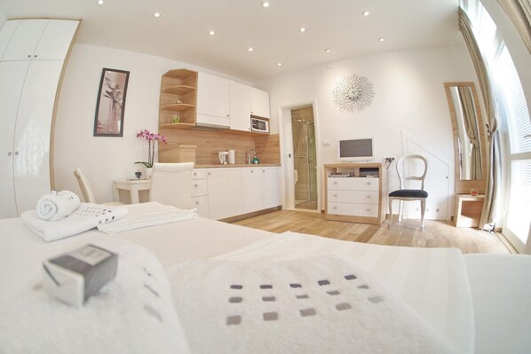 Een moderne hotelkamer met een groot bed, een bureau, een stoel, een televisie en een douche.