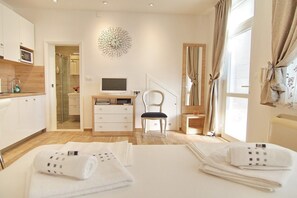 Een hotelkamer met een bed, bureau, stoel, televisie en een douche.