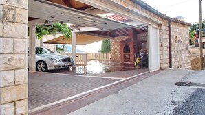 En lukket garage med en bil parkeret indeni, en murbygning og et dræningssystem.