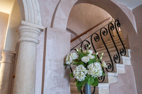 Classical architecture meets elegant design, featuring a prominent column, curved archway, and ornate staircase.