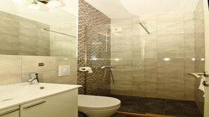 Un baño moderno con ducha envuelta en vidrio, inodoro blanco y tocador con espejo.