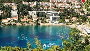 A coastal town with a large body of water, buildings with red roofs, and a prominent white building with a modern design.