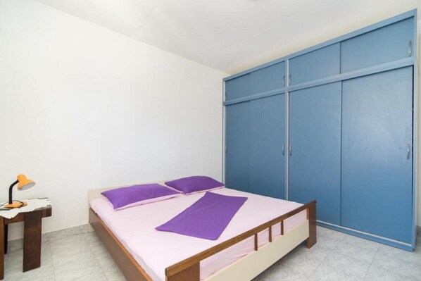 Quarto com cama, escrivaninha com luminária e guarda-roupa azul.
