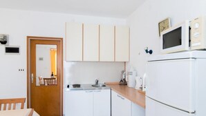 A compact kitchen with white cabinets, a microwave, a refrigerator, and a sink.