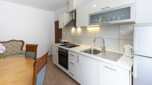 A compact kitchen with white cabinets, a stainless steel sink, a built-in oven, and a microwave. - Guest House Rooms Rose- Comfort Double Room with Balcony and Sea View (Molunat)