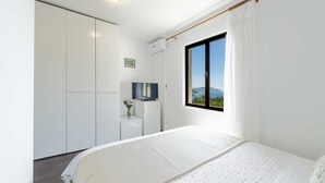 A bedroom with a bed, a TV, a wardrobe, and a window with a view of the outdoors. - Guest House Rooms Rose- Comfort Double Room with Balcony and Sea View (Molunat)
