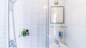 Et moderne badeværelse med et brusekabine i glas, en vask og et spejl.