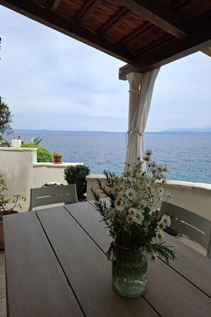 Une table avec un vase de fleurs, une chaise blanche et une vue sur la mer.