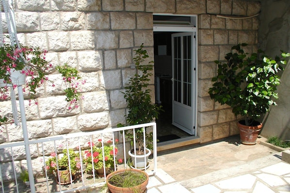 Enter a tranquil space with a balcony offering a view, surrounded by lush greenery and rustic charm.