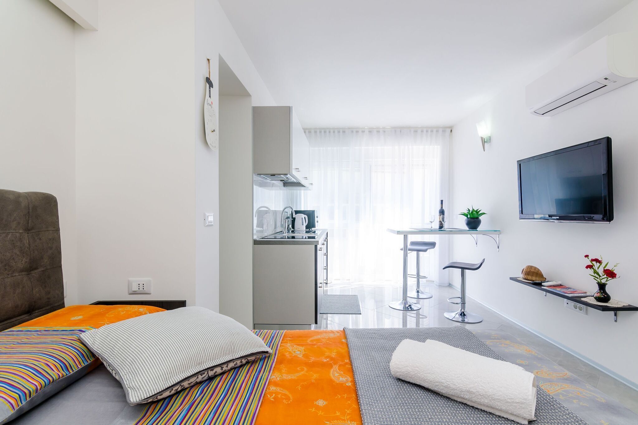 Una camera d'albergo compatta con un letto, un angolo cottura, una TV e vista sulla cucina.