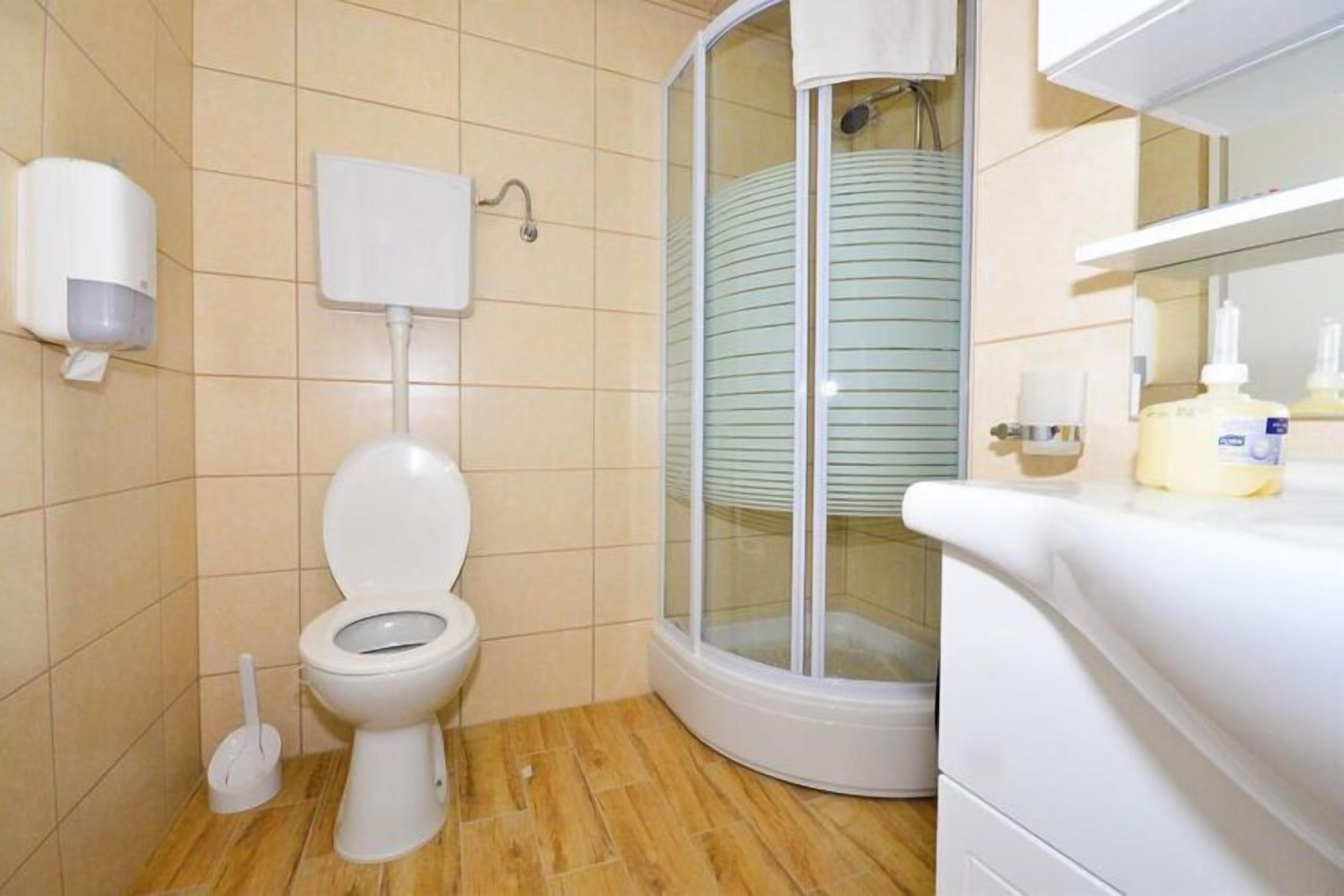 Ein Badezimmer mit Toilette, Handtrockner, Duschkabine und Waschbecken mit Pflegeprodukten.