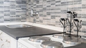 Een keuken met een modern ontwerp, voorzien van een roestvrijstalen fornuis, een spoelbak en een betegelde achterwand.