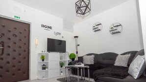 Een moderne woonkamer met een zwarte bank, een wit wandrek en een televisie.