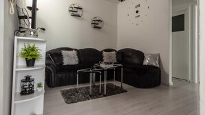 Een moderne woonkamer met een zwarte leren bank, een ronde salontafel en decoratieve wandkunst.