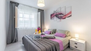 Een moderne slaapkamer met een bed, nachtkastje en een raam met gordijnen.