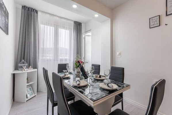 Uma sala de jantar com uma mesa de mármore posta para quatro pessoas, cadeiras pretas e um aparador branco com um letreiro escrito 'Smile'.