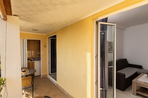 Ett kompakt bostadsutrymme med ett litet kök, en matplats och en sittgrupp med soffa och bord.