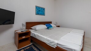 A neatly made bed with a white comforter and pillows, a bedside table with a lamp, and a wall-mounted TV. - Apartments Belenum - One-Bedroom Apartment with Balcony and Sea View (no.3) (Mlini)
