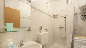 Un baño con lavamanos, inodoro, ducha y lavadora.