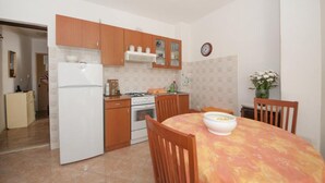Una cocina compacta con armarios de madera, un refrigerador blanco, una estufa y una mesa de comedor con sillas.