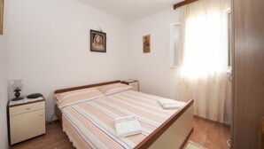 Un dormitorio con cama, mesita de noche, lámpara y dos cuadros en la pared.