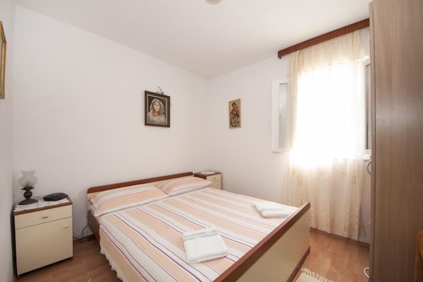 A bedroom with a bed, a nightstand, a lamp, and two framed pictures on the wall.