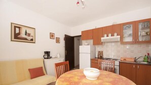 Una cocina compacta con armarios de madera, un refrigerador y un comedor con mesa y sillas.