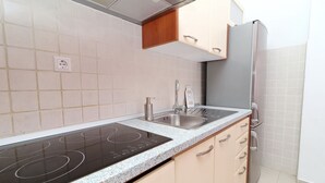 Una cocina equipada con estufa integrada, dos fregaderos y refrigerador.