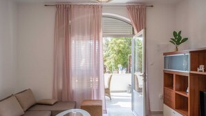 Una sala de estar moderna con un sofá, una mesa de centro de vidrio y un mueble bajo para televisión de madera.