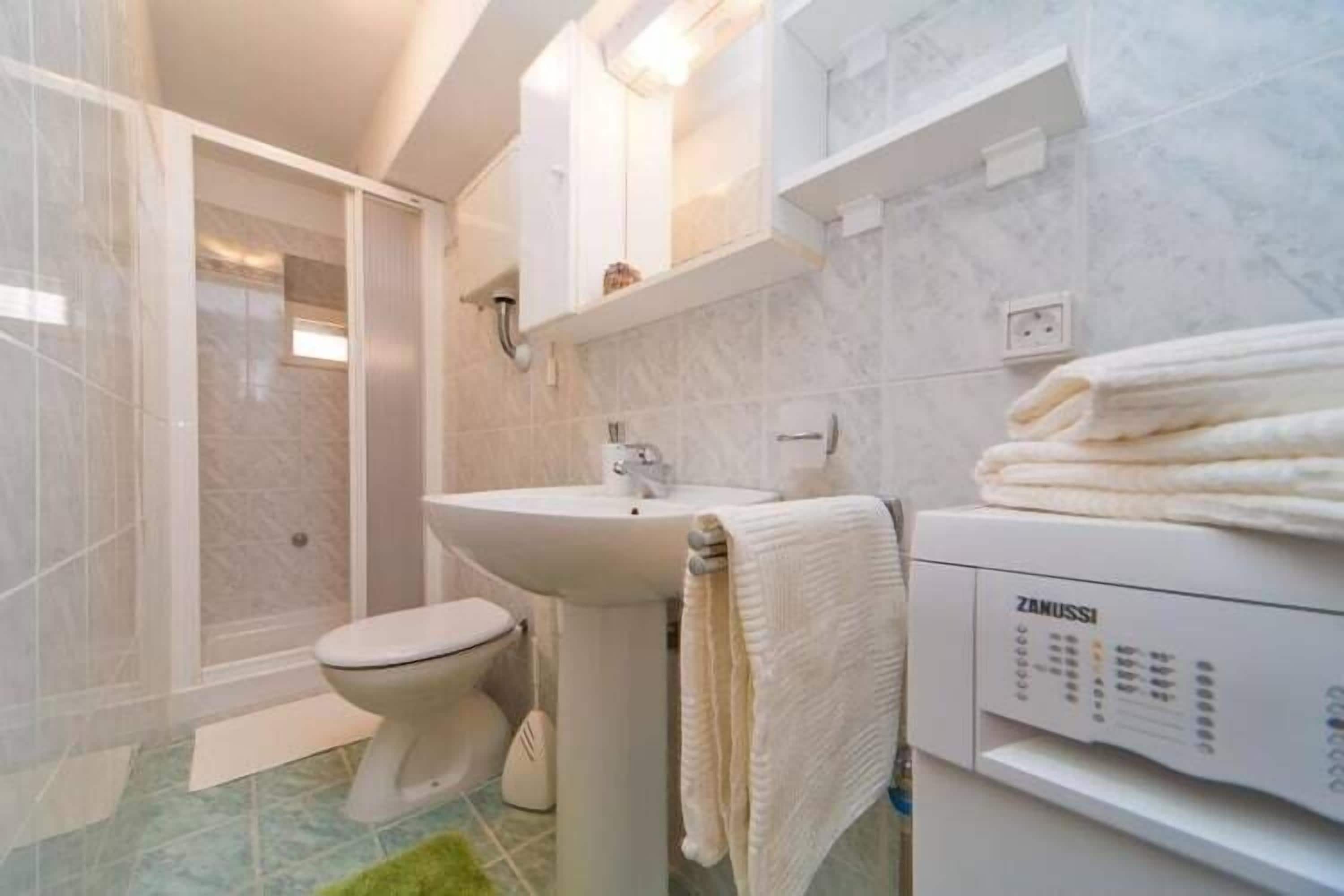 Un baño moderno con inodoro, lavamanos y ducha integrada.