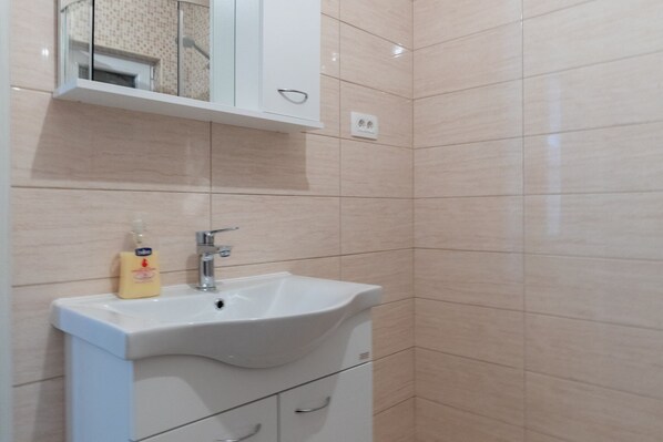 Un baño con un lavabo blanco, un espejo encima y un mueble abajo.