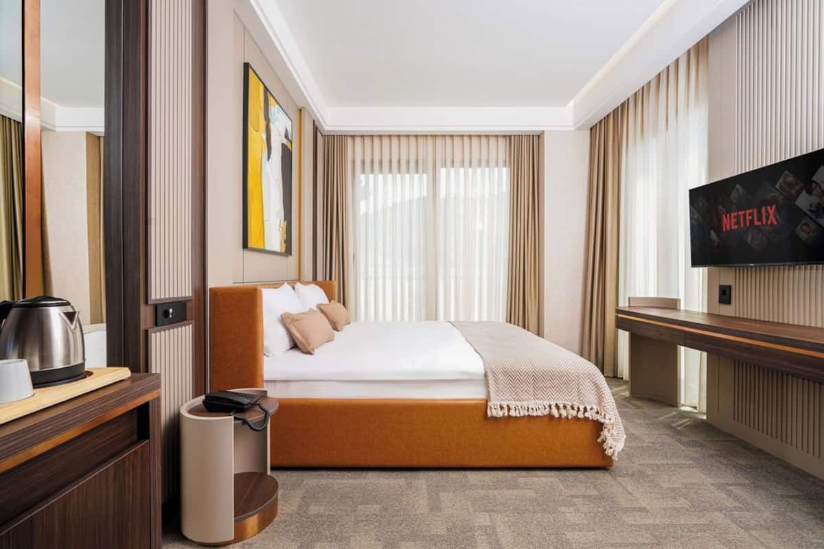 A hotel room with a bed, a TV, a coffee maker, and a bedside table.
