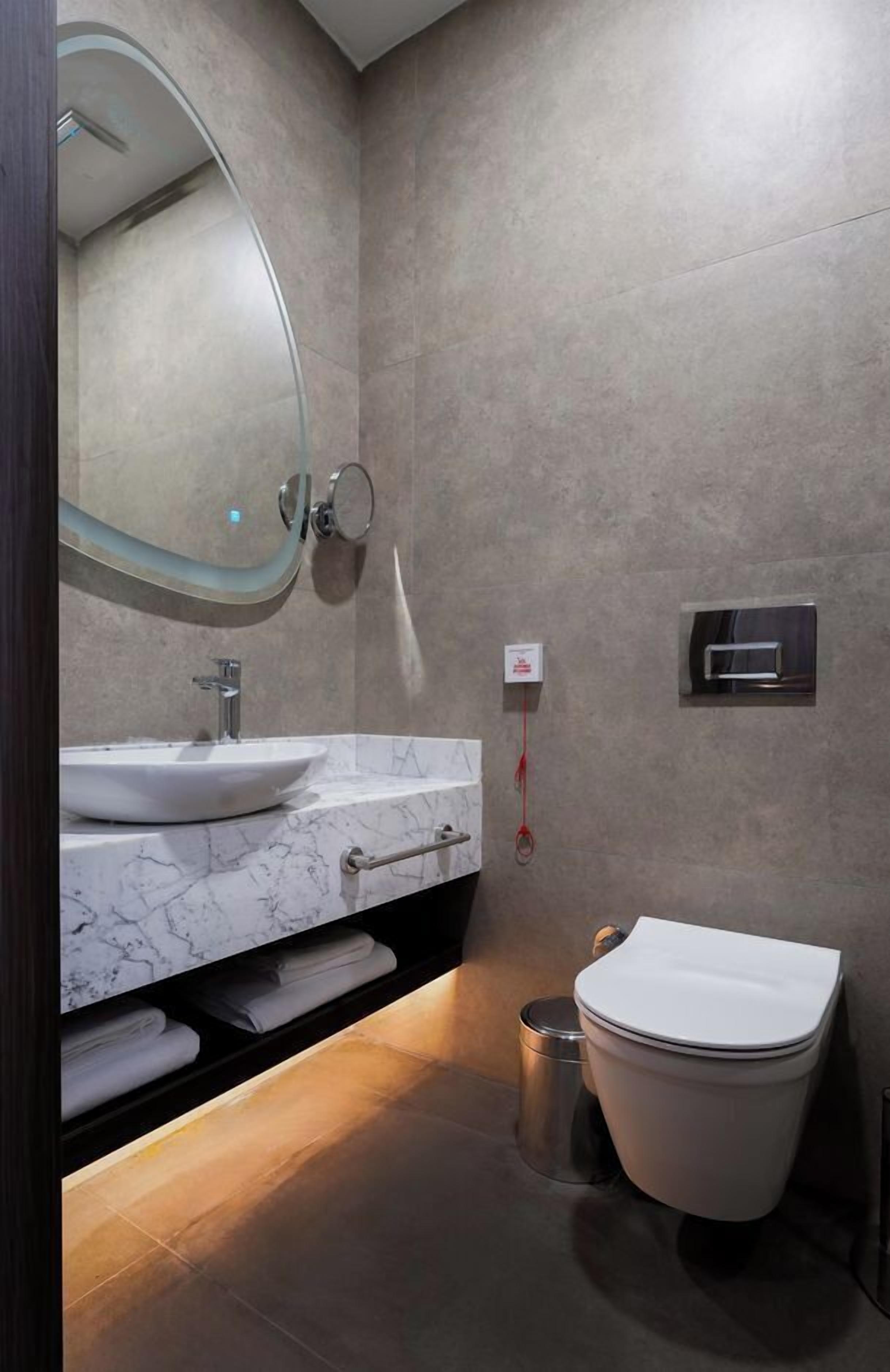 Ein modernes Badezimmer mit Marmorwaschtisch, Toilette und einer integrierten Dusche.