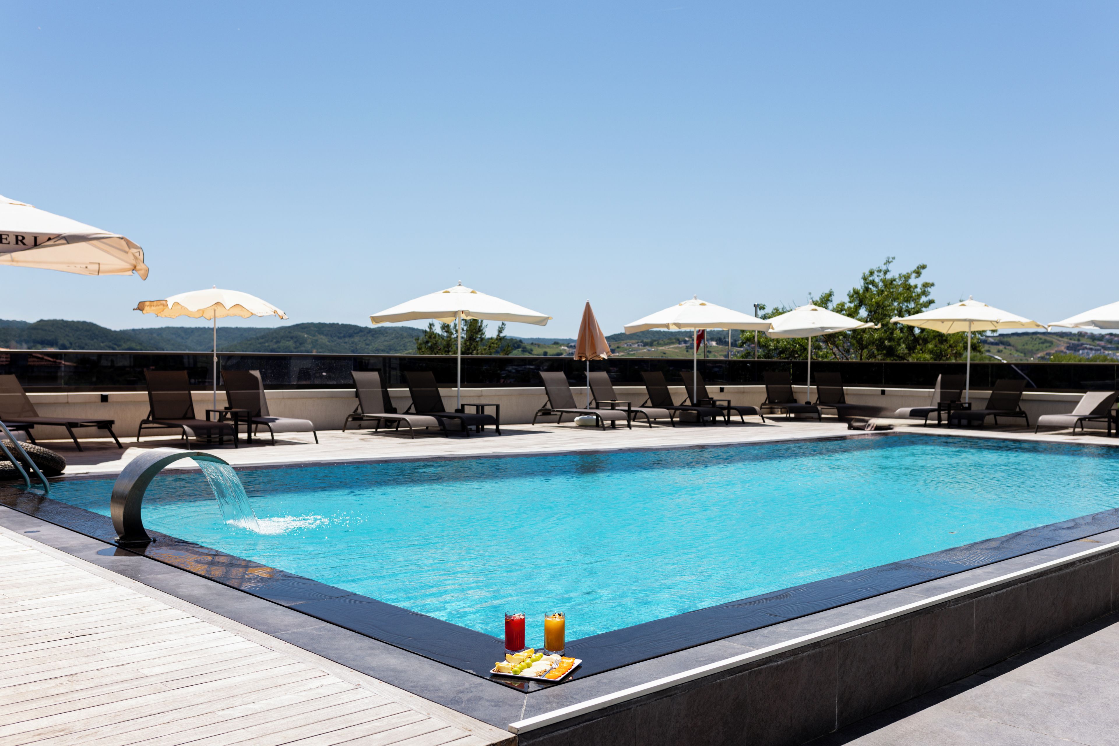 A swimming pool with lounge chairs and umbrellas, surrounded by a wooden deck.