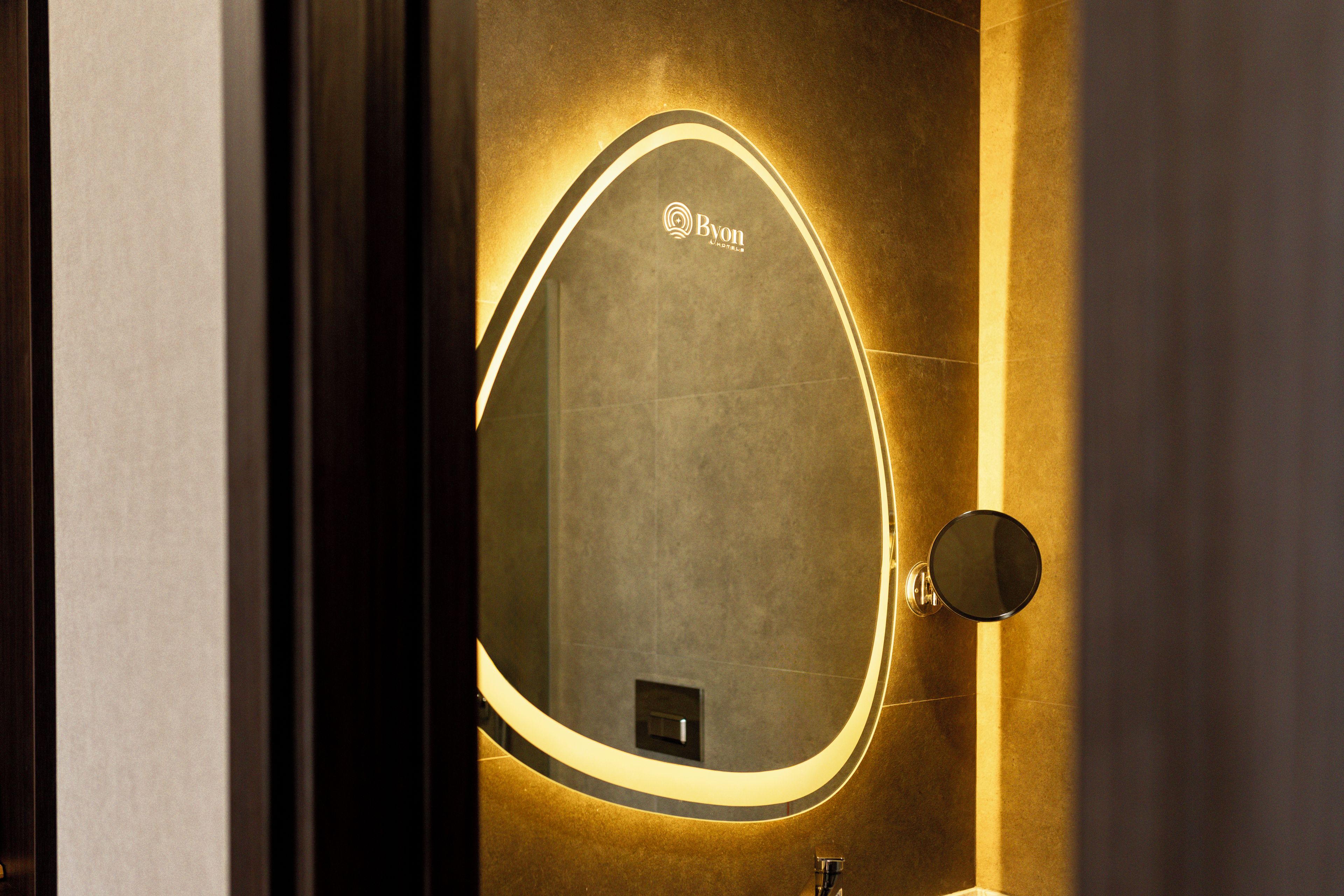 Un baño con un espejo ovalado grande, un lavamanos y un aplique de pared.