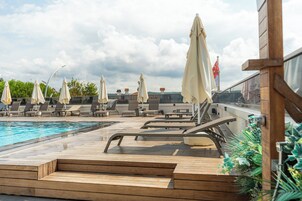 Uma área de piscina no terraço com espreguiçadeiras e guarda-sóis.