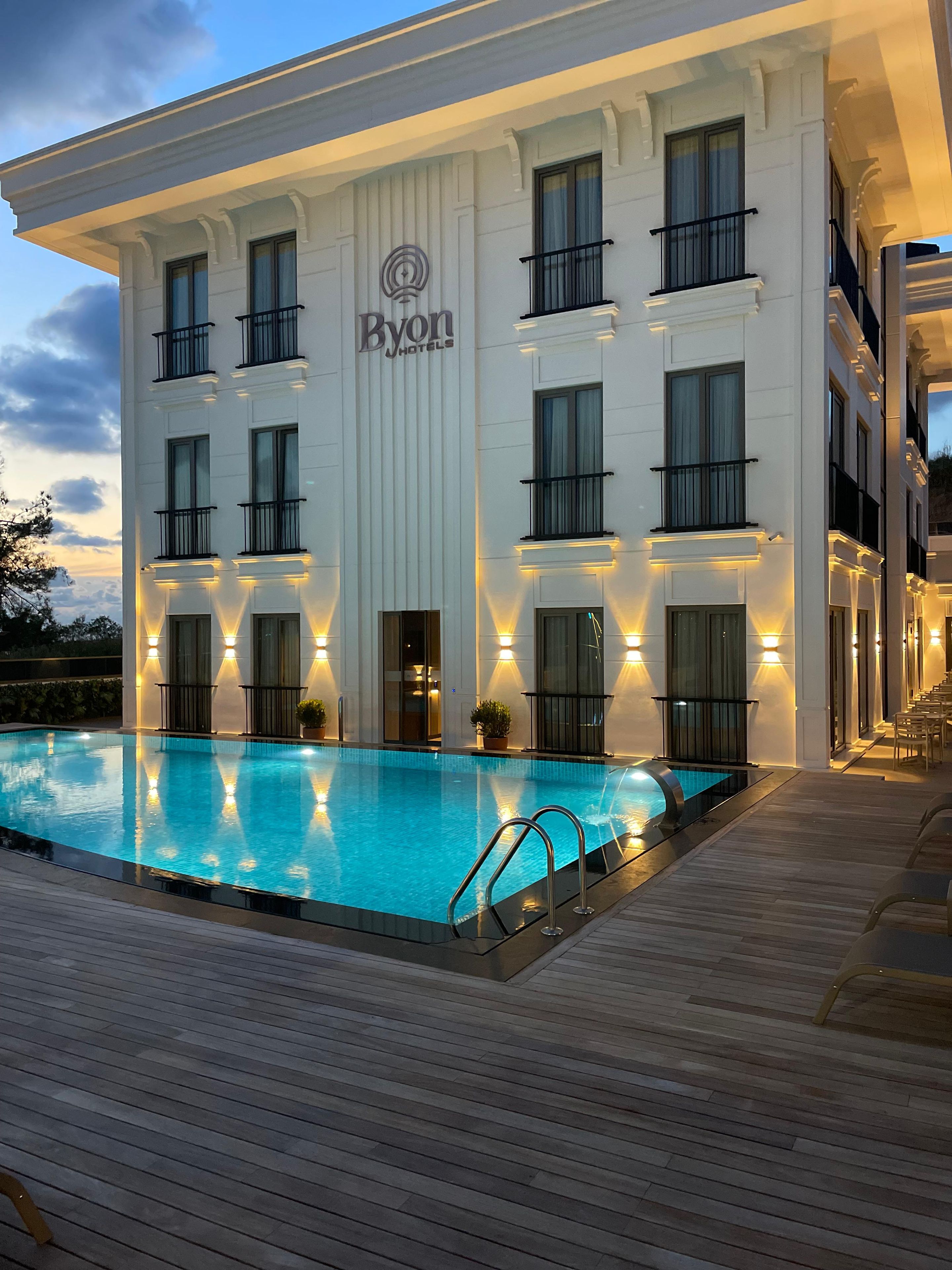 A hotel building with a swimming pool, multiple balconies, and a sign reading 'Byon Hotels'.