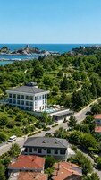 Un hotel con piscina, rodeado de vegetación y vistas al mar.