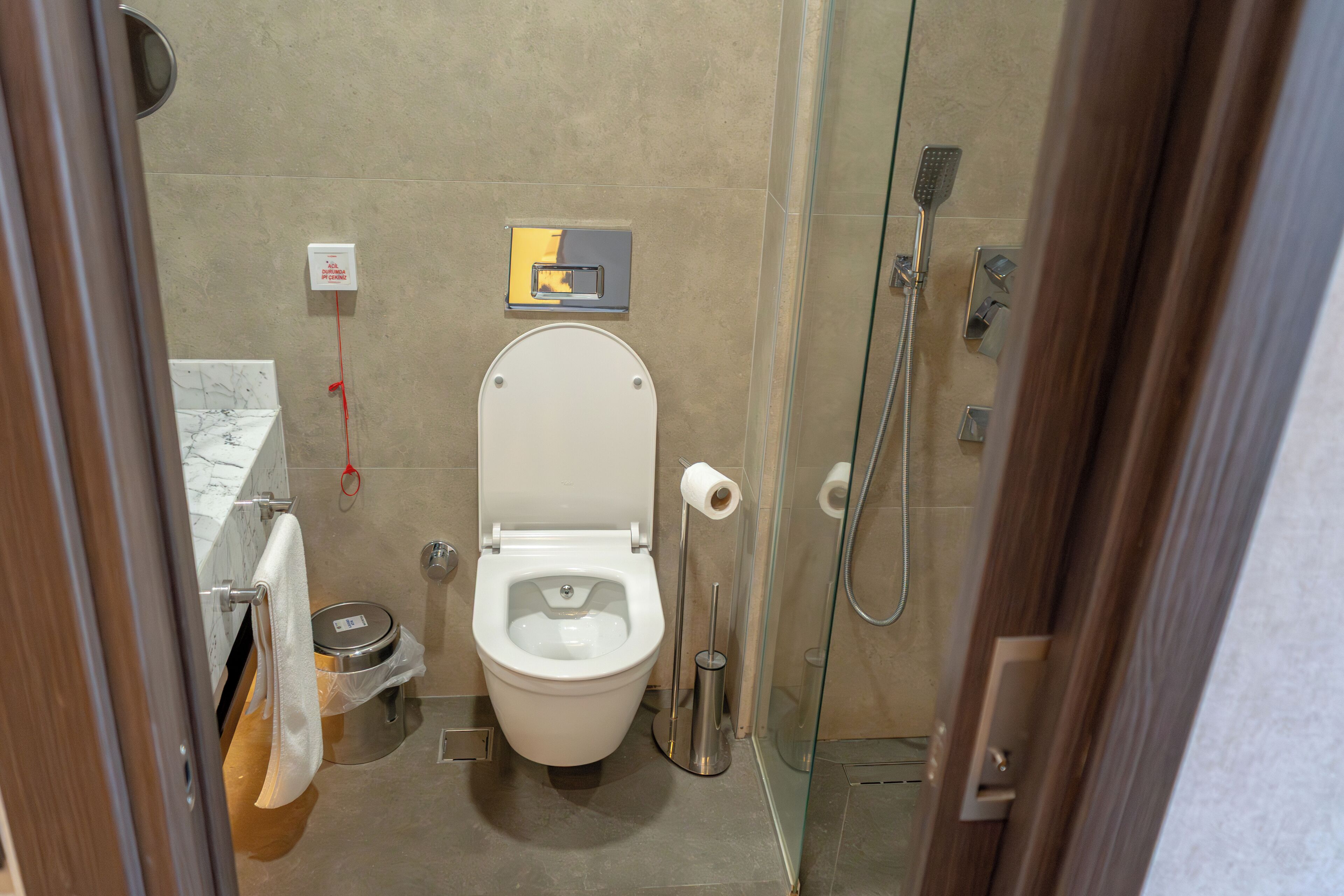 A modern bathroom with a toilet, shower, and glass-enclosed shower stall.