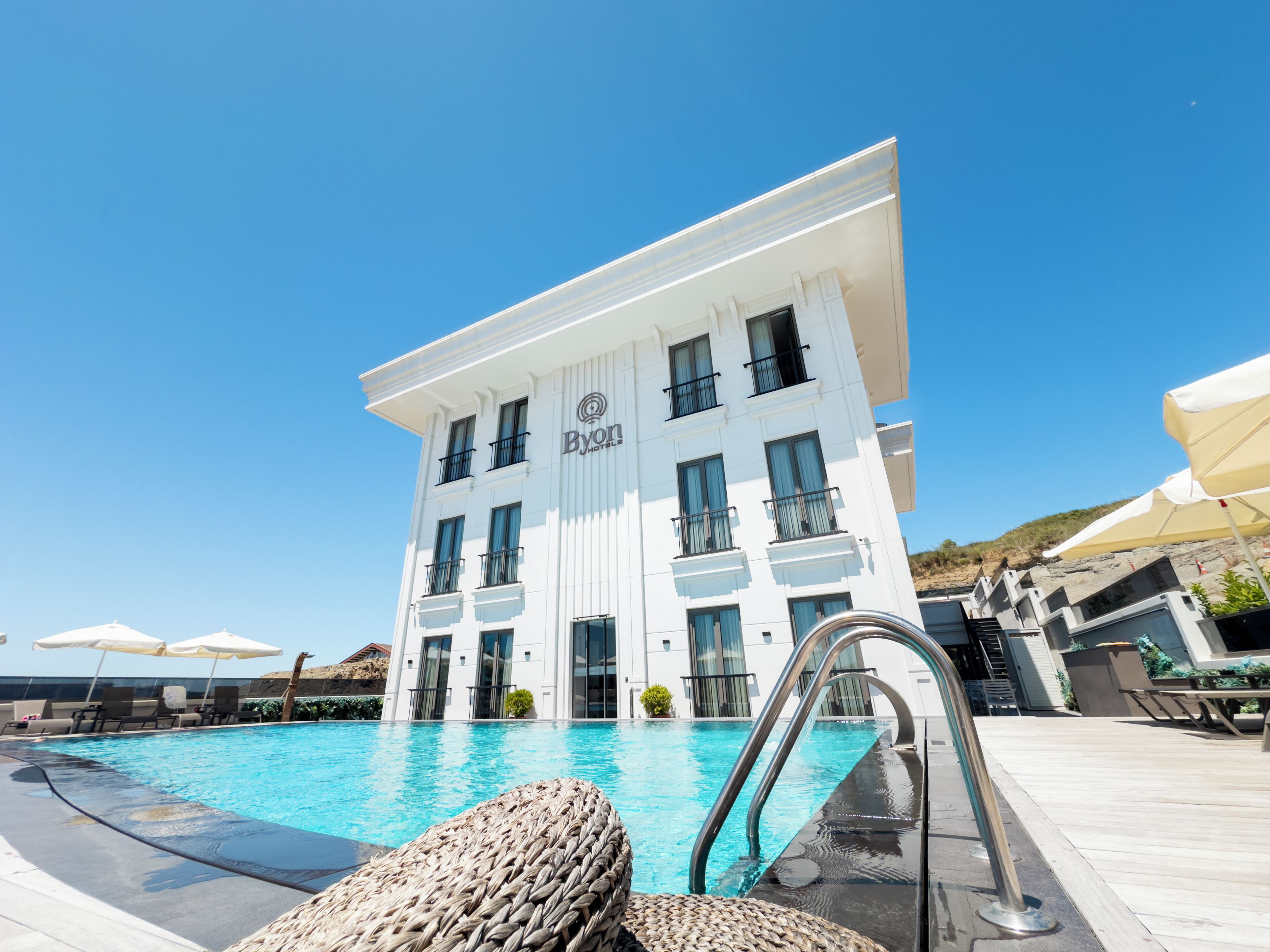 Un hotel con piscina, mobiliario exterior y un cielo azul despejado.