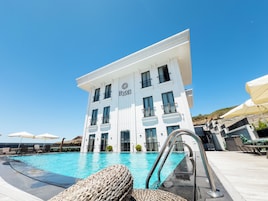 Un hotel con piscina, mobiliario exterior y un cielo azul despejado.